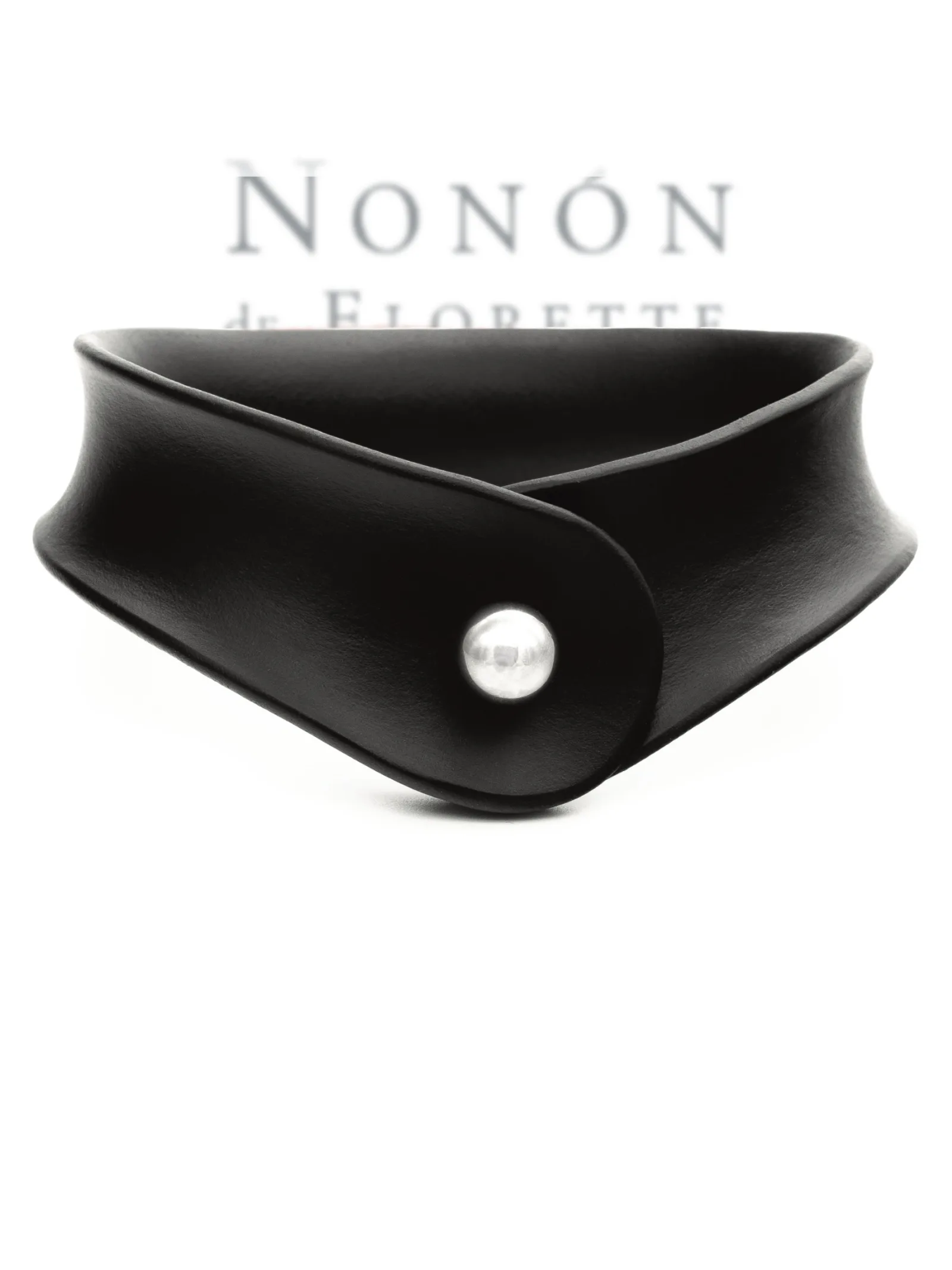 Wide black leather collar by NoNón with a curved shape and metal ball fastening, against a white background.
